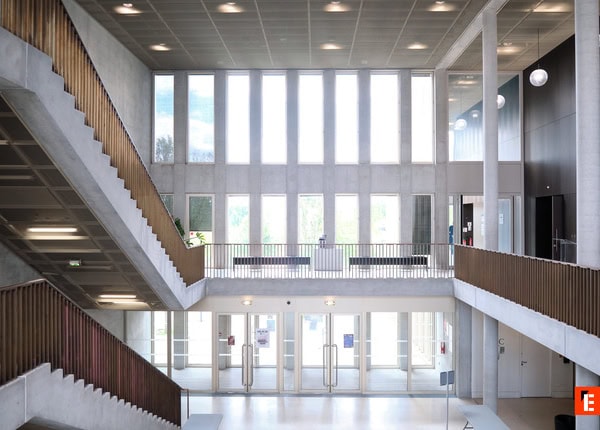 Étudiants en travail déquipe autour dun ordinateur portable dans une salle de classe moderne.