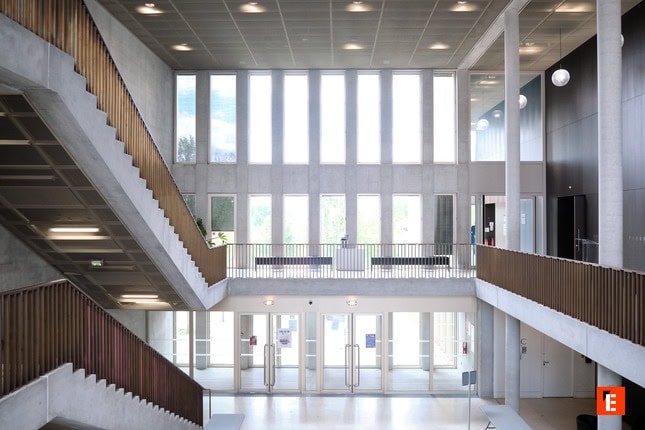 Étudiants en travail déquipe autour dun ordinateur portable dans une salle de classe moderne.