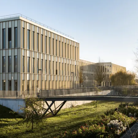 Complexe de bureaux et campus modernes avec pont piéton, façades verticales et espaces paysagers.