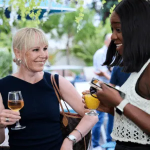 Deux femmes discutent à lapéro dans un jardin, verre de vin rosé.