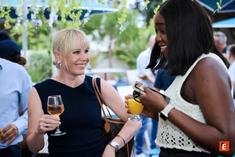 Deux femmes discutent à lapéro dans un jardin, verre de vin rosé.