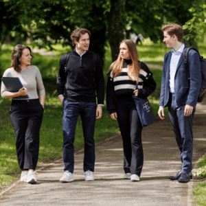 Quatre étudiants marchant ensemble dans un parc verdoyant, discussion et sacs à dos.