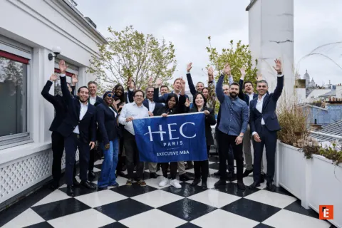 Cohorte HEC Paris MBA Exécutif sur toit-terrasse, groupe divers célébrant et souriant.