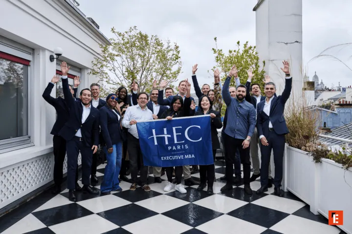 Cohorte HEC Paris MBA Exécutif sur toit-terrasse, groupe divers célébrant et souriant.