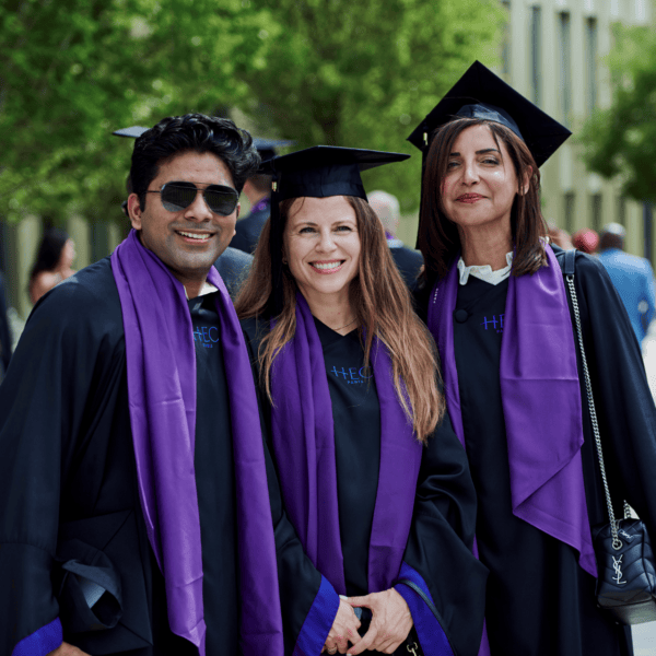Trio de diplômés HEC en toges et écharpes violettes lors de la remise des diplômes.