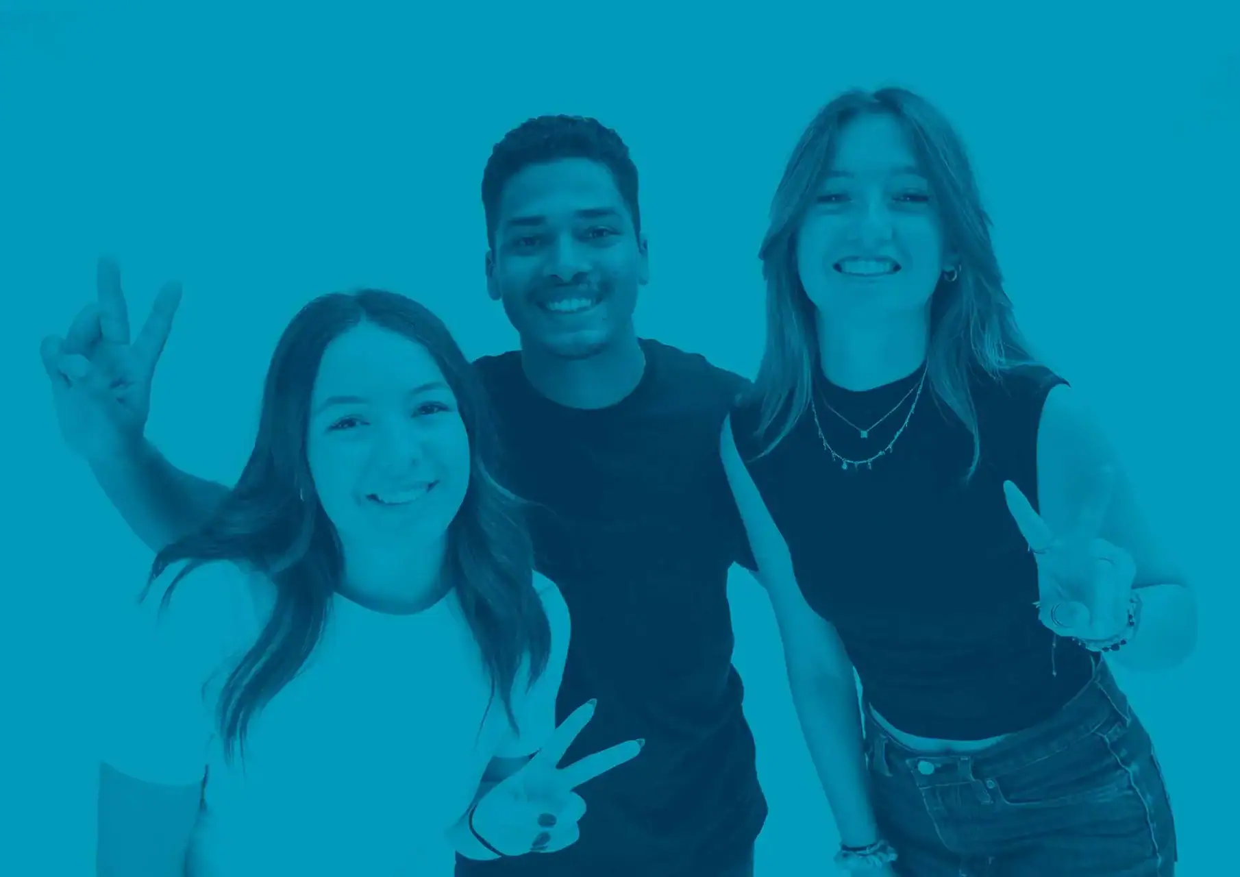 Portrait de groupe de trois jeunes souriants en teinte cyan, fond uni.