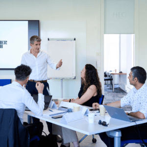 Réunion en bureau moderne avec écran de présentation, participants et ordinateurs portables.