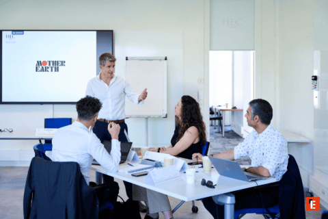 Réunion en bureau moderne avec écran de présentation, participants et ordinateurs portables.