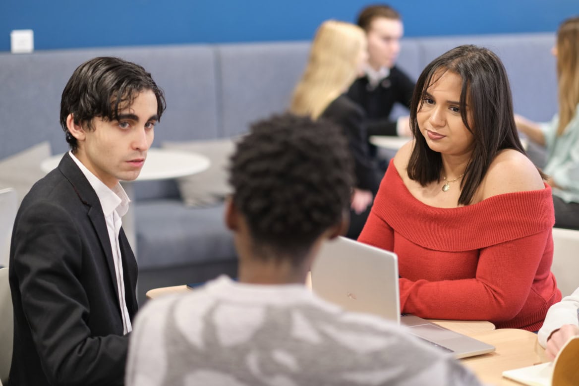 Étudiants en lounge collaborant autour d’un ordinateur dans un espace d’étude moderne.