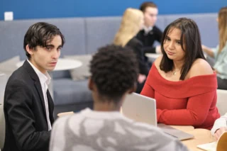 Étudiants en lounge collaborant autour d’un ordinateur dans un espace d’étude moderne.