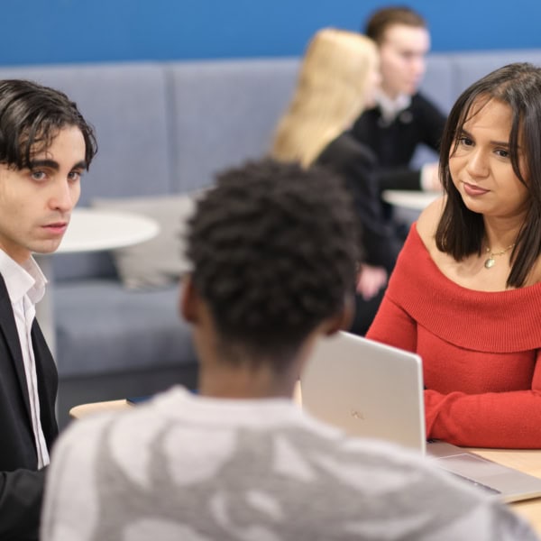 Étudiants en lounge collaborant autour d’un ordinateur dans un espace d’étude moderne.