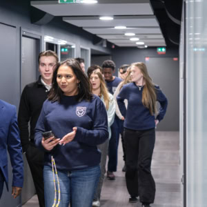Groupe de jeunes professionnels marchant dans un couloir de bureau moderne.