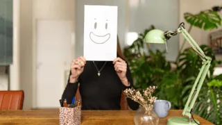 Une femme porte un smiley devant son visage.