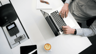 Un ordinateur vu de dessus. Quelqu'un tape sur le clavier.