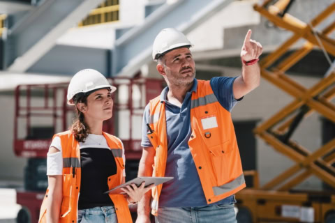 Homme et femme portant casque blanc et chazuve orange sur un chantier