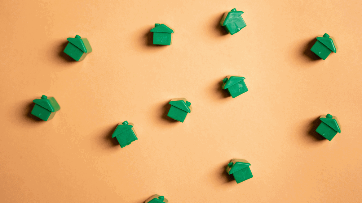 Des maisons vertes de Monopoly éparpillées sur un fond orange.