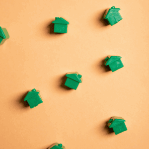 Des maisons vertes de Monopoly éparpillées sur un fond orange.