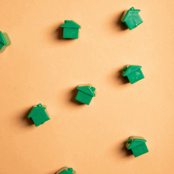 Des maisons vertes de Monopoly éparpillées sur un fond orange.