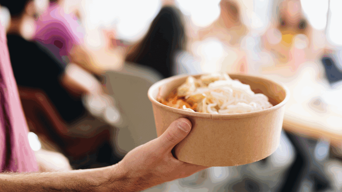 Une personne tient dans sa main un plat à emporter.