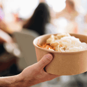 Une personne tient dans sa main un plat à emporter.