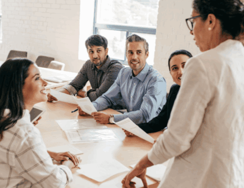 Un groupe de personne dont une debout en réunion pour illustrer l'Executive-master-management-online