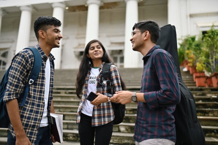 Un groupe d'étudiants entrain de parler devant un bâtiment