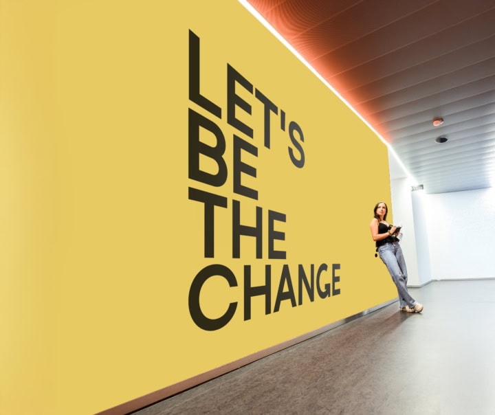 Une étudiante se tenant debout devant un mur jaune