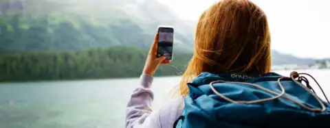 Une femme tenant son téléphone dans les mains face aux montages