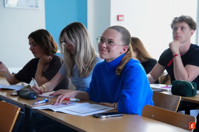 Étudiants en cours, prise de notes dans une salle de classe lumineuse.