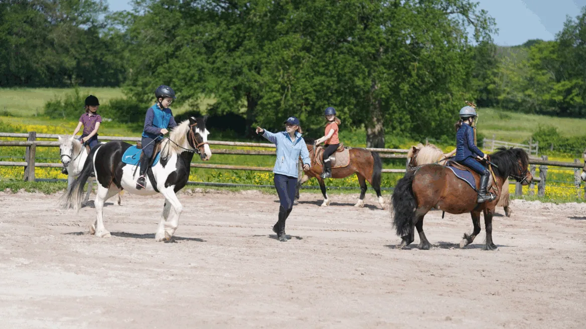 Un professeur d'équitation donne cours à ses élèves.
