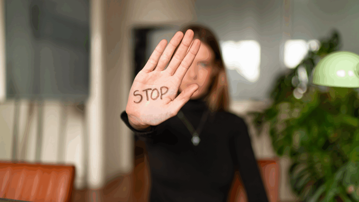 Une femme tend la main sur laquelle il est écrit Stop.
