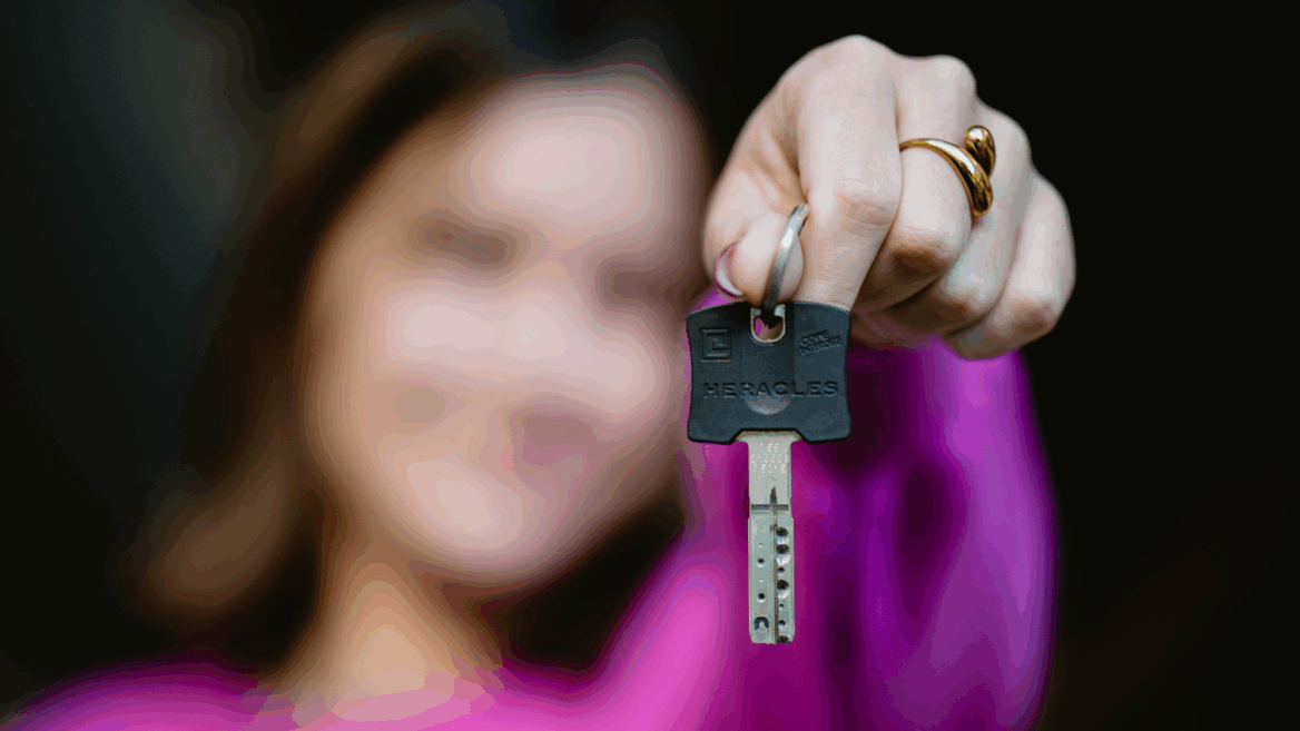 Une jeune femme tient une clé devant son visage.
