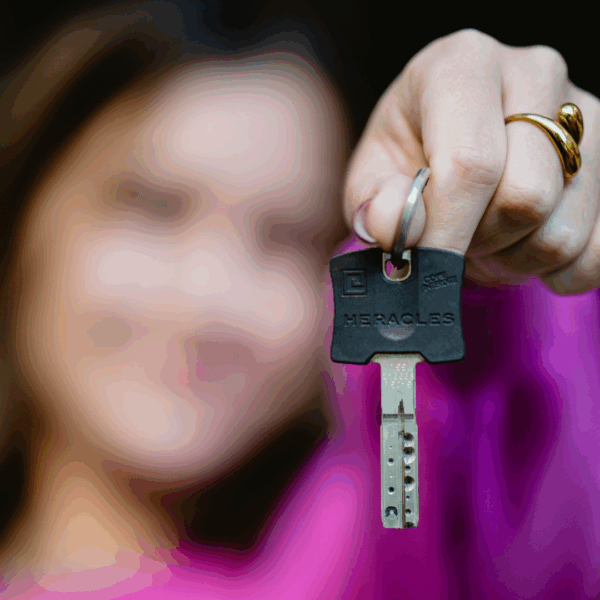 Une jeune femme tient une clé devant son visage.