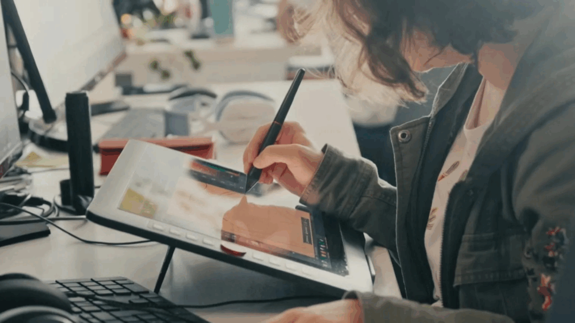 Une jeune femme dessine sur une tablette graphique.