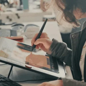 Une jeune femme dessine sur une tablette graphique.