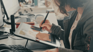 Une jeune femme dessine sur une tablette graphique.