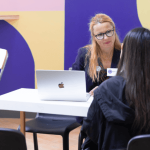 enseignante discutant avec une étudiante assise sur un bureau