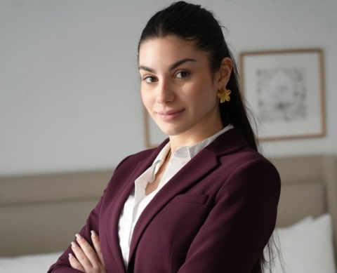 Une femme portant un blazer bordeaux posant les bras croisés