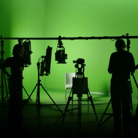 Vue sur un groupe de personne devant un fond vert dans un studio