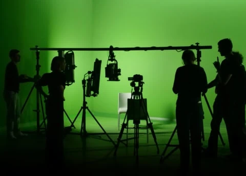 Vue sur un groupe de personne devant un fond vert dans un studio