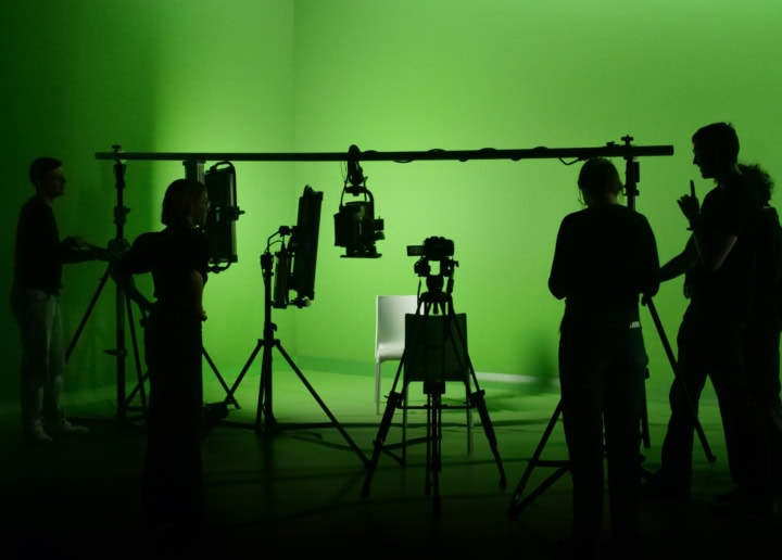 Vue sur un groupe de personne devant un fond vert dans un studio