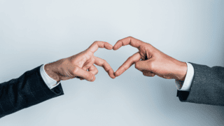 Deux hommes forment un coeur avec leurs mains.