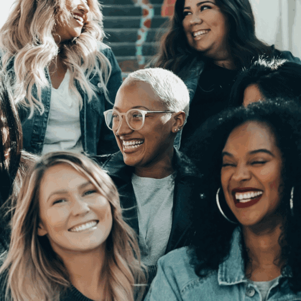 Un groupe de femmes assises sur des escaliers sourient toutes ensemble.