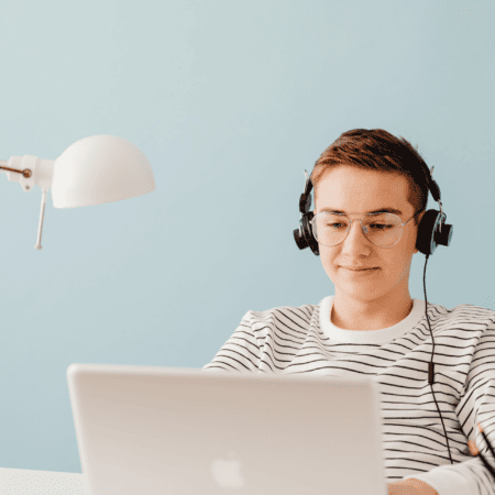 Étudiant concentré avec casque et ordinateur portable au bureau minimaliste, télétravail et étude.