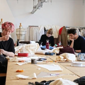 Exposition de mannequins haute couture devant bannière rouge 1841, silhouettes structurées et déconstructives.