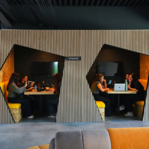 Espace de travail partagé moderne avec table, ordinateurs portables et personnes concentrées.