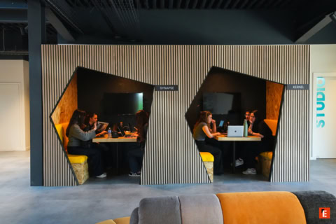 Espace de travail partagé moderne avec table, ordinateurs portables et personnes concentrées.