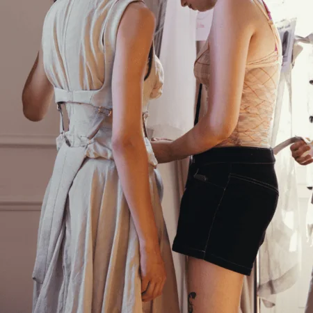 Atelier : deux modèles ajustent une robe lors dun essayage couture en coulisses.