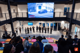 Atelier Honda : présentation dune voiture sur grand écran devant public en gradins.