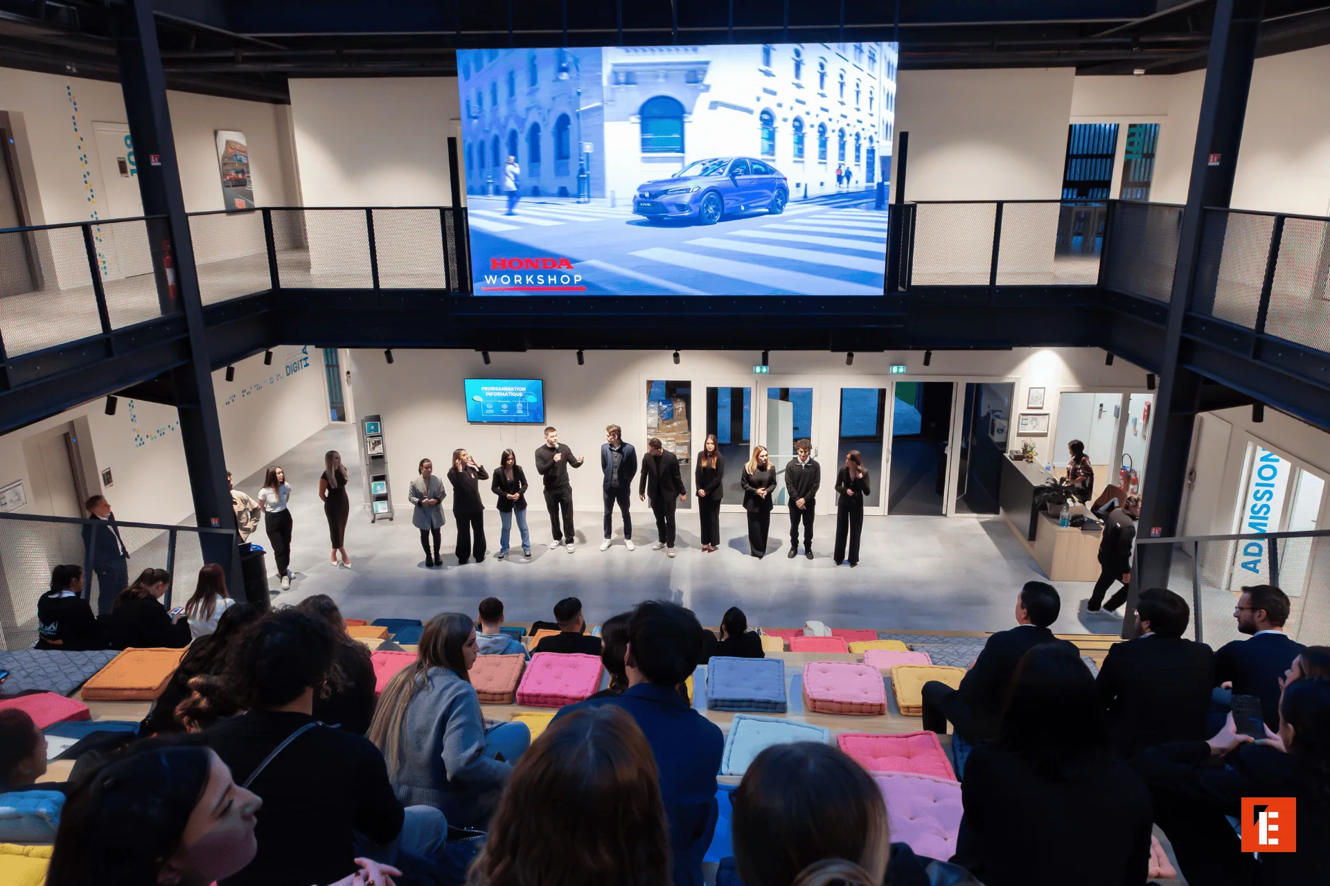 Atelier Honda : présentation dune voiture sur grand écran devant public en gradins.